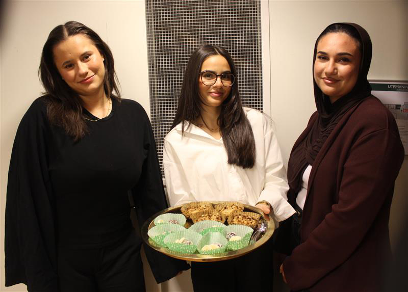 Tre tjejer står och håller i kakfat.