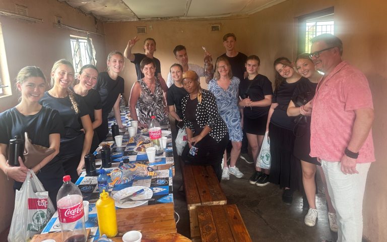 Gruppfoto med elever och lokalbefolkning runt ett bord